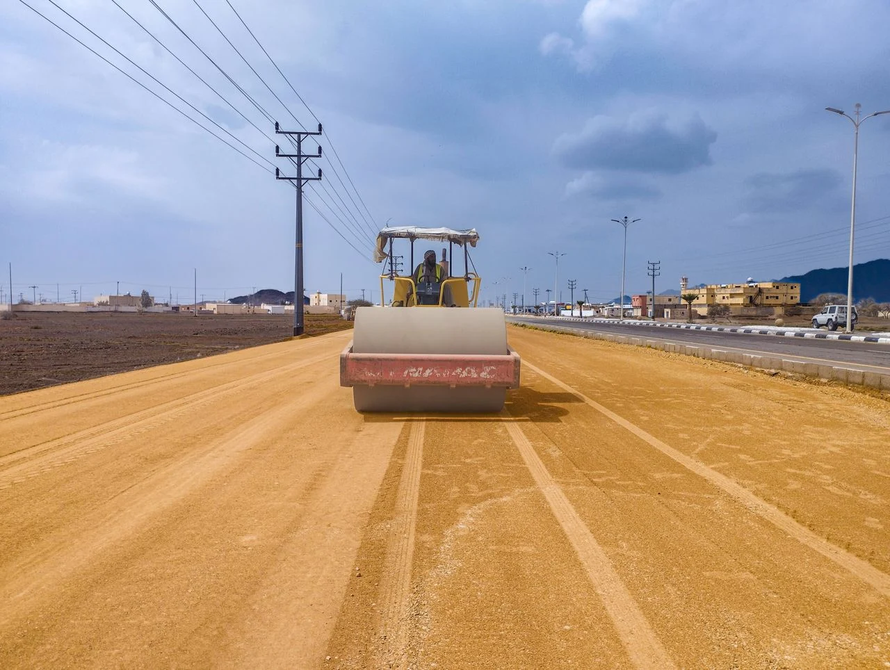 Road roller compacting a newly graded road surface